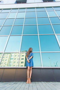 Full length of woman standing against blue sky