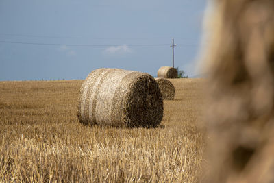 Hay bales on field against sky