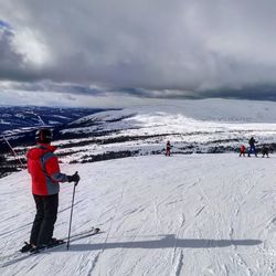 Rear view of people walking on snow covered mountain against sky