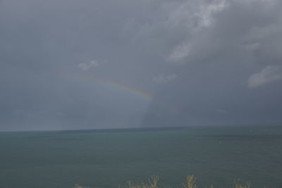 Scenic view of rainbow over sea against sky