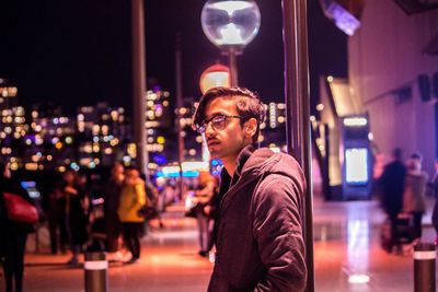 Portrait of young man looking away in city at night