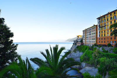 Scenic view of sea by buildings against clear sky
