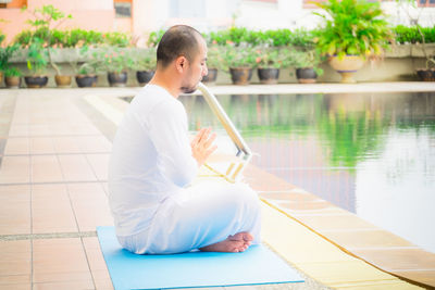 Man sitting by swimming pool in lake