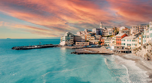 Scenic view of sea and buildings against sky during sunset