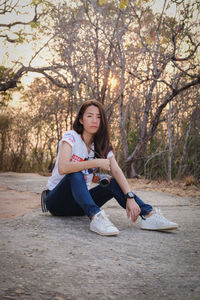 Portrait of beautiful young woman sitting on tree