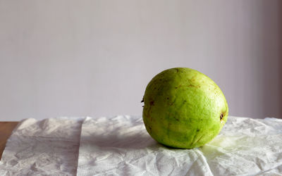 Close-up of apple on table against wall