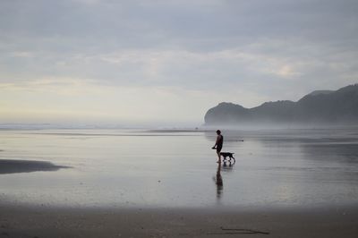 Man on beach against sky during sunset