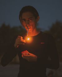 Young woman holding illuminated string lights