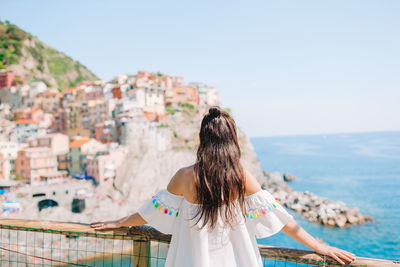 Rear view of woman looking at cityscape against sky