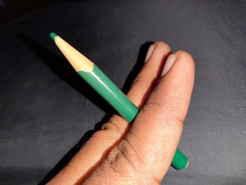 Close-up of hand holding pencils on table