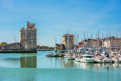 Sailboats moored on sea against buildings in city