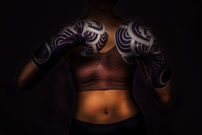 Midsection of woman standing against black background