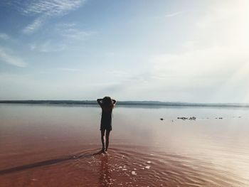 Rear view of man standing on beach against sky