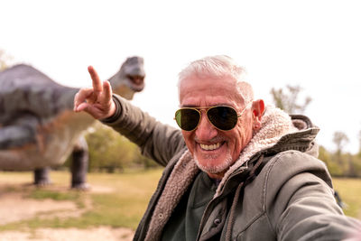 Portrait of young man wearing sunglasses against trees