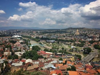 Aerial view of cityscape against cloudy sky