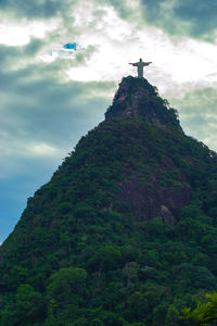 Low angle view of cross on rock against sky