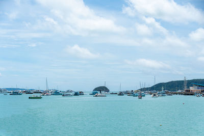 Sailboats in sea against cloudy sky