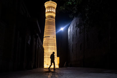 Silhouette man standing by illuminated building at night