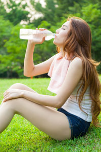 Side view of smiling young woman sitting at park