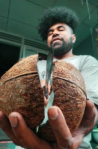 Young man holding broken coconut