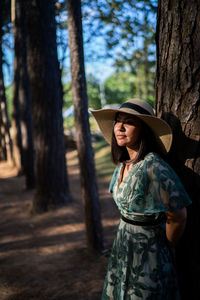 Young woman standing by tree trunk