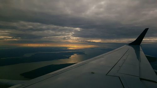 Airplane flying over sea against cloudy sky