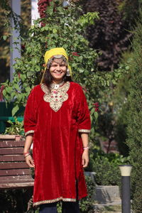 Portrait of young woman standing by plants