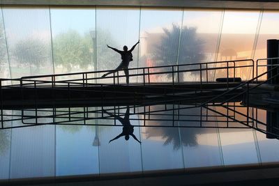 Silhouette man jumping in swimming pool against sky