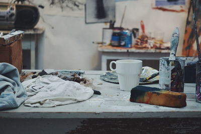 Messy painting equipment on table at workshop