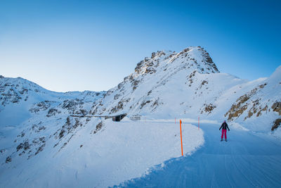 Person skiing on snowcapped mountain against clear sky