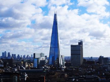 Modern buildings in city against cloudy sky