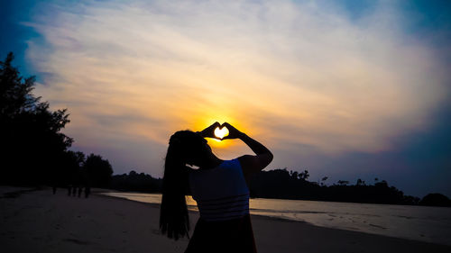 Silhouette woman standing on land against sky during sunset