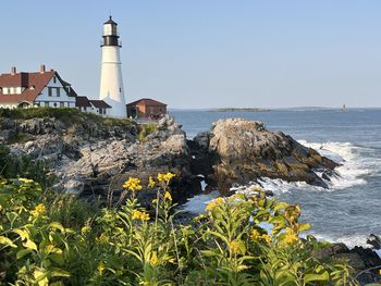 Lighthouse by sea against sky