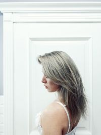 Side view of young woman standing against wall