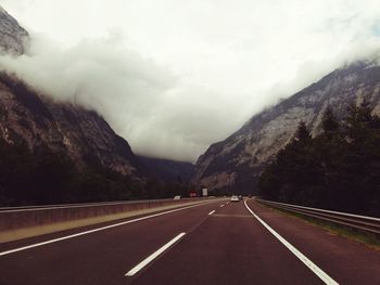 Empty road by mountains against sky