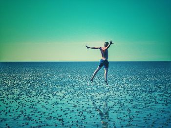 Full length of man surfing in sea against sky