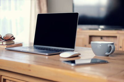 Close-up of laptop with mobile phone and coffee cup on table