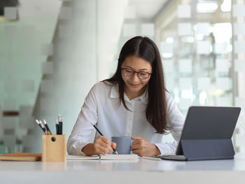 Young woman using phone on table