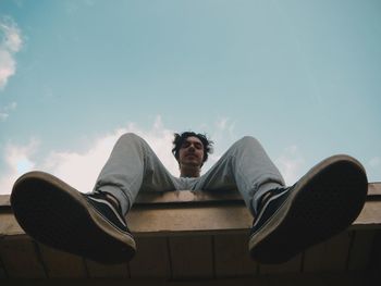 Portrait of young man sitting on seat against sky