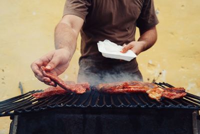Midsection of man grilling meat against wall