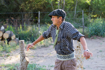 Man looking away while leaning on fence