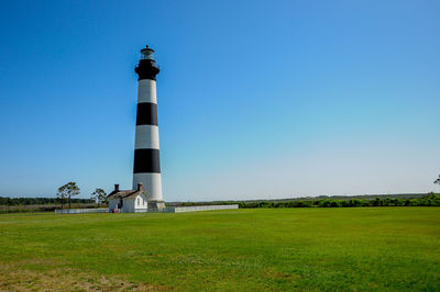 Lighthouse on field against clear sky