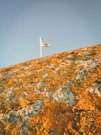 Low angle view of flag on mountain against clear sky