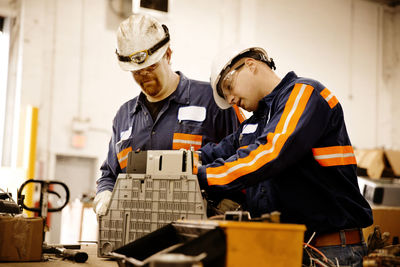 Male workers examining electrical equipments in recycling plant