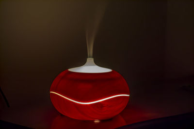 Close-up of illuminated electric lamp with smoke on table