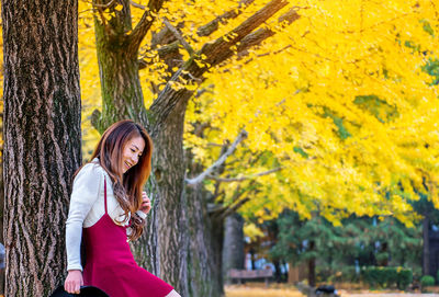 Woman standing by tree during autumn