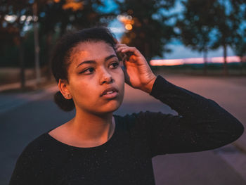 Portrait of young woman looking away in city