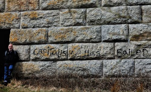 Full length of man standing against brick wall