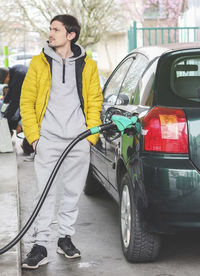 Handsome young caucasian man refuels his car