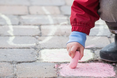 Low section of boy drawing with chalk on footpath